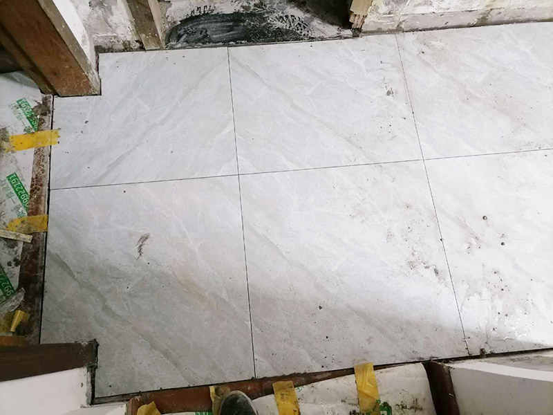 走廊地面貼磚案例:首先，要先清理現(xiàn)場，先灑適量的水以利施，在施工地面撒上水泥粉，以掃把撥弄均勻，以增加與水泥沙漿的粘著性，在施工地點(diǎn)測出水平落差最高的地方：首先在每一面的墻上，分別測出其水平線。 然后，以每一面墻的水平落差的最高點(diǎn)基準(zhǔn)，以水泥沙漿為標(biāo)記，做為打底的水平基準(zhǔn)，將水泥與沙以1：3的比例混合成水泥沙漿，以約六尺的木尺打底，徹底抹平，拉放樣線，再次撥灑水泥粉，以增加瓷磚的粘著性，在貼瓷磚的過程中，一方以槌柄輕敲瓷磚，讓它能確實(shí)吃漿。另一方面，并以水平尺測量，確保瓷磚水平，貼完之后，先以海綿沾水將瓷磚擦干凈。